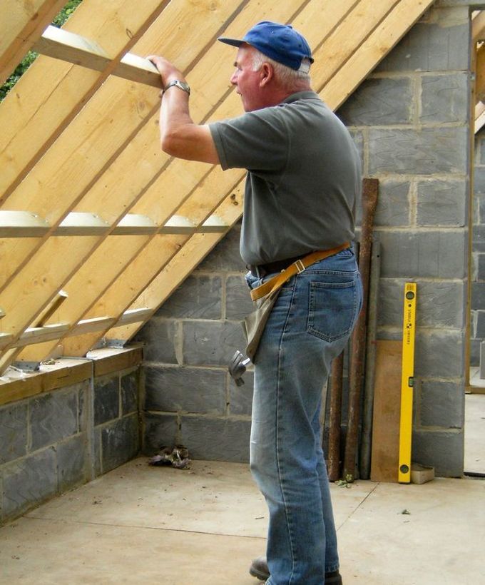 Carpenter fitting timber rafters for a new roof