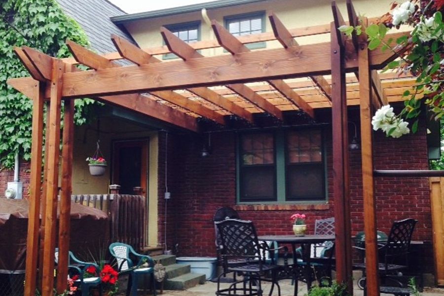 Timber pergola over a brick patio with outdoor dining furniture
