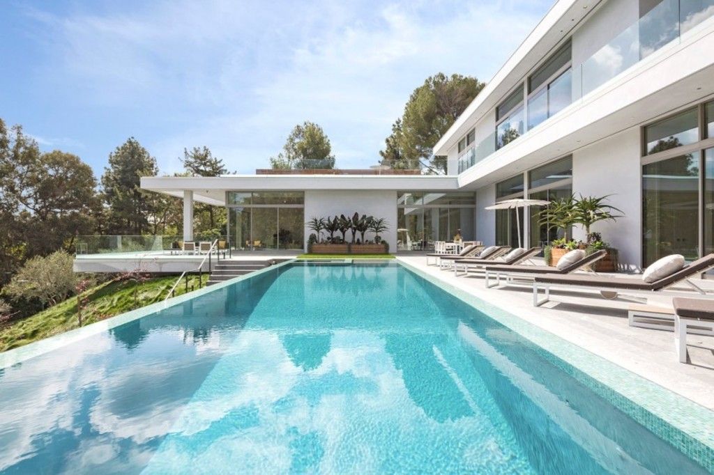 Modern home with glass walls and a long swimming pool