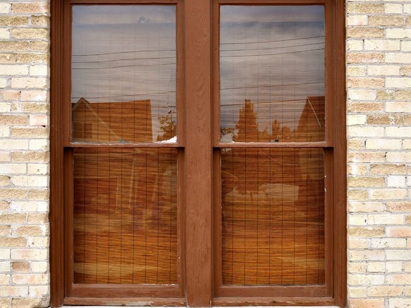 Arched timber window set in a pale brick wall